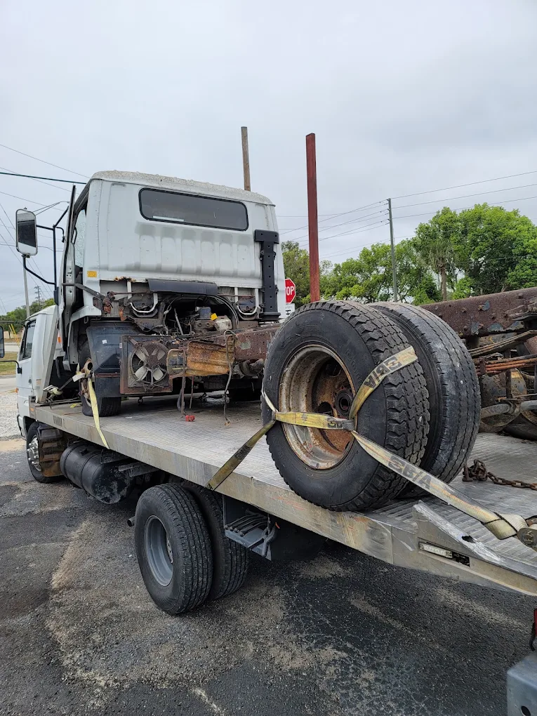 Tow truck carrying large commercial vehicle tire on flatbed trailer