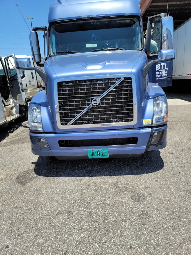 Blue Volvo semi truck with chrome grille parked at commercial lot