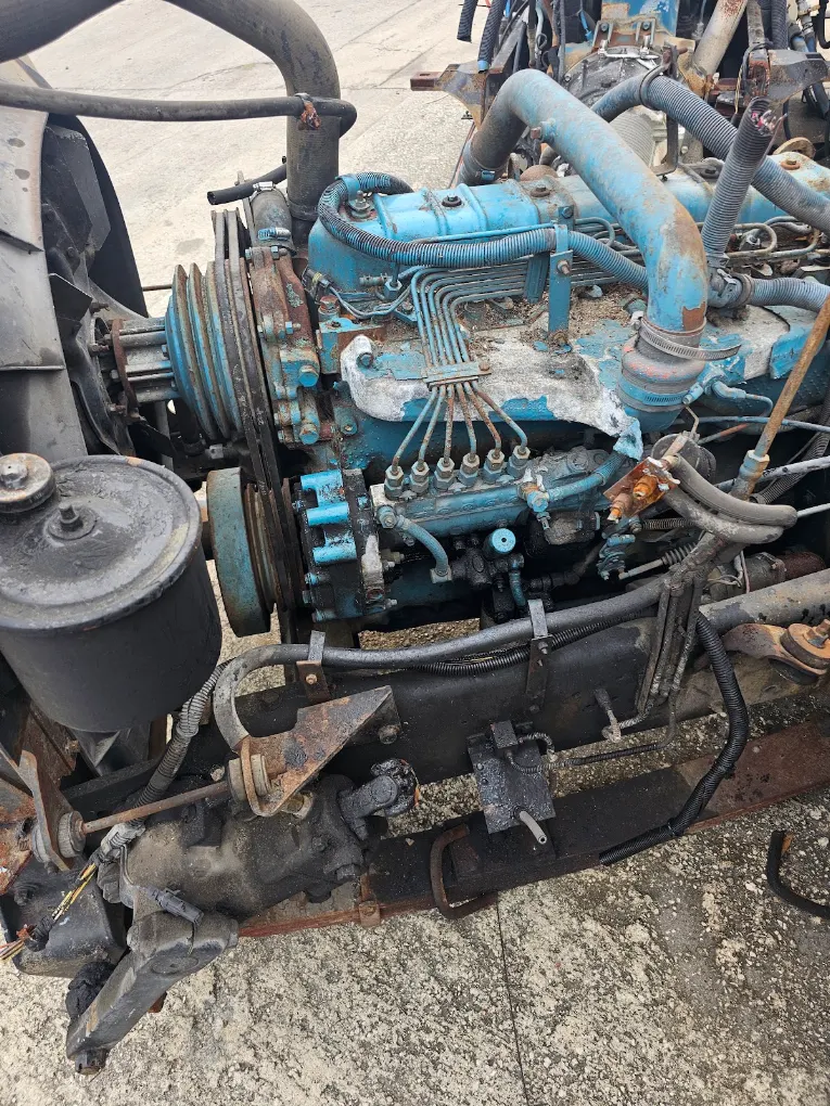 Used blue diesel engine with pulley system and hoses on concrete surface