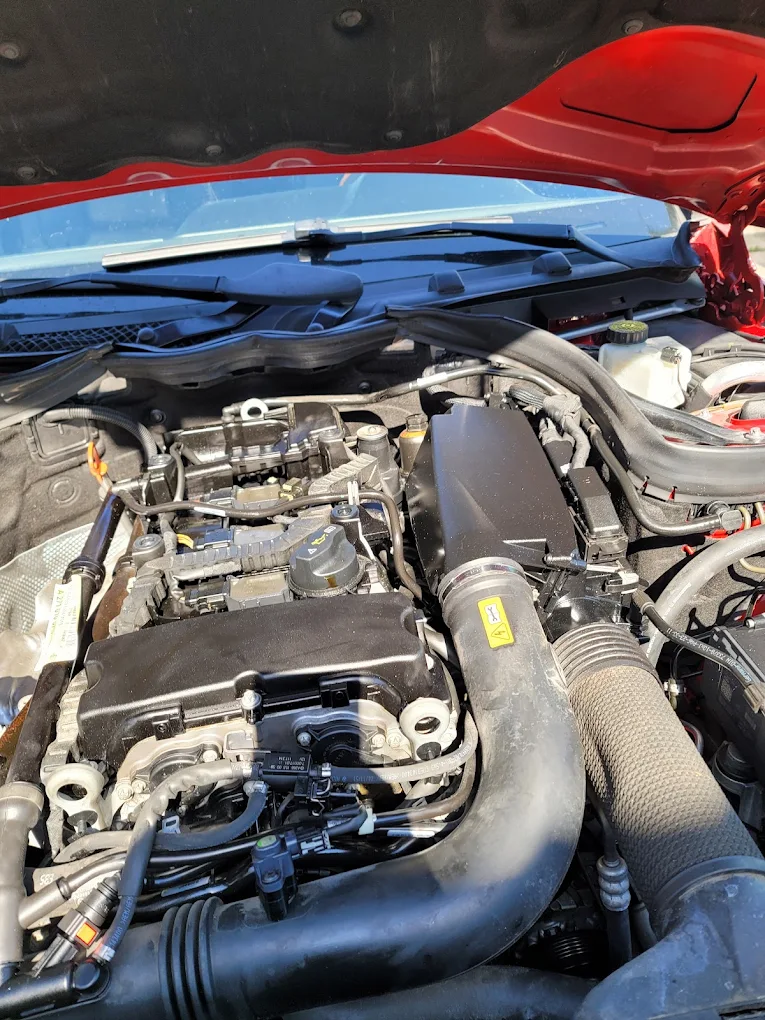 Open engine bay of red sports car showing motor and blue hood cover