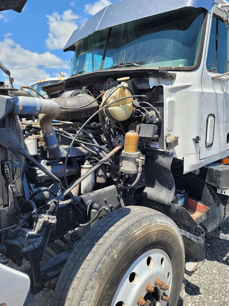 Open engine compartment of white commercial truck showing diesel engine and mechanical components