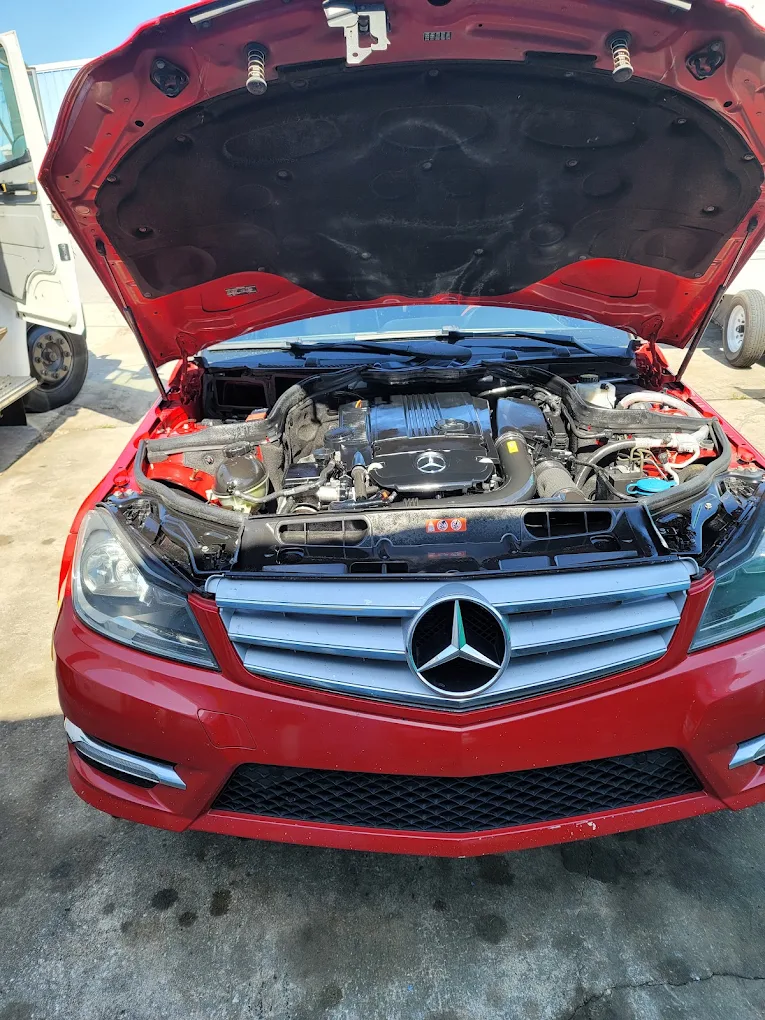 Red Mercedes-Benz with open hood displaying engine compartment at dealership